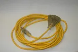 Coiled yellow outdoor extension cord with a lighted three-outlet end