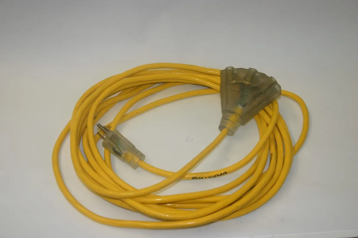 Coiled yellow outdoor extension cord with a lighted three-outlet end