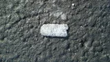 A single lead wheel weight lying on asphalt