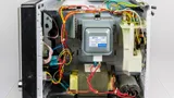 Microwave oven with the outer case removed, showing the magnetron, transformer, capacitor, and wiring
