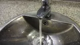 Stainless steel sink with water running from a single-lever tap