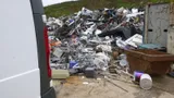 White van parked beside a large pile of mixed scrap metal and appliances