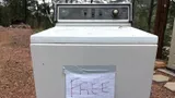 Old top-load washing machine at the roadside with a handwritten FREE sign taped to the front