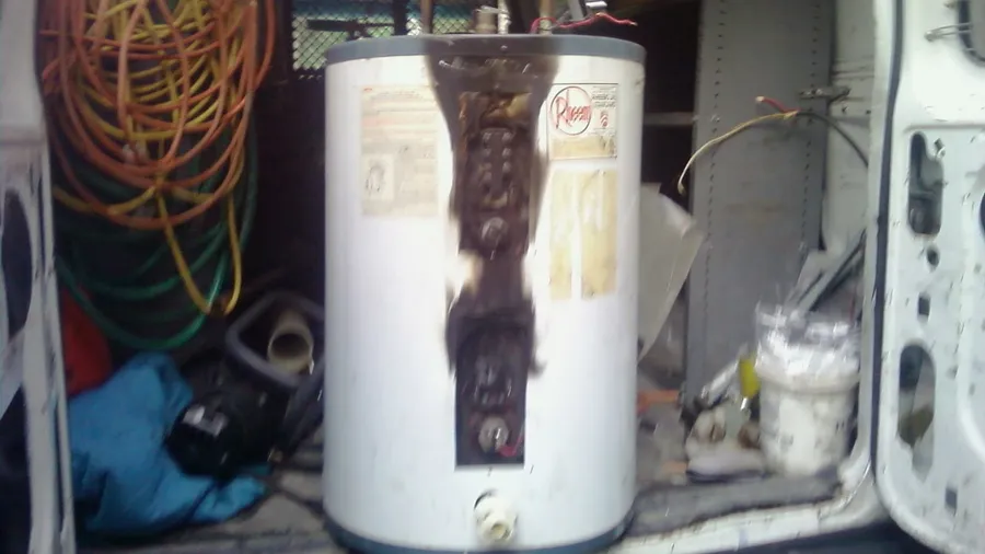Old electric water heater loaded into the back of a work van