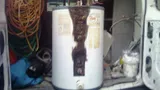 Old electric water heater loaded into the back of a work van