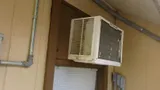 Window air conditioner mounted through an exterior wall, its finned condenser coil facing outdoors